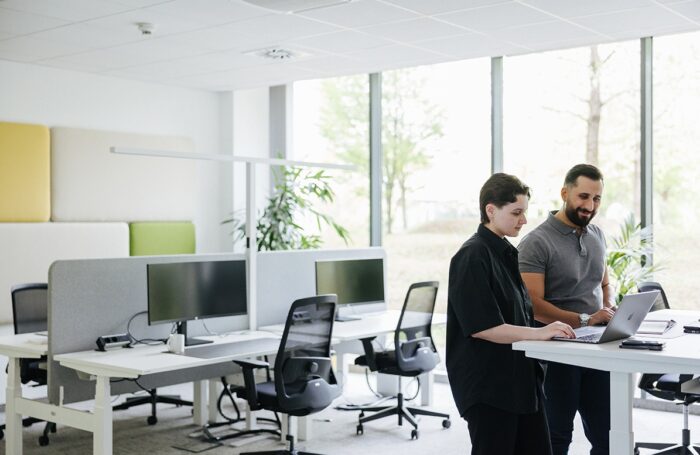 Öffentlichen Raum im Büro und zwei Menschen am hohen Tisch arbeiten mit Laptop