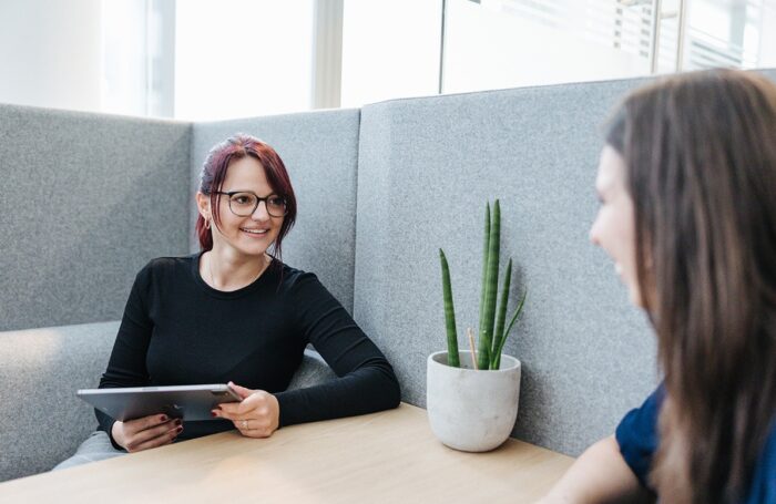 Zwei Menschen sitzen auf Lounge Büro Garnitur und unterhalten, lachen